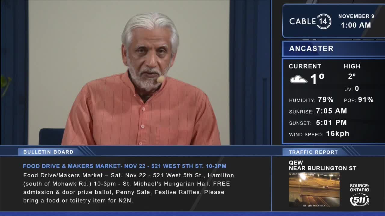 A man with a white beard and a rust-colored shirt speaks into a microphone, likely on Cable 14 in Hamilton, Ontario. The screen shows the weather in Ancaster, along with a bulletin about a food drive and makers market.
A man with a white beard and a rust-colored shirt speaks into a microphone, likely on Cable 14 in Hamilton, Ontario. The screen shows the weather in Ancaster, along with a bulletin about a food drive and makers market.