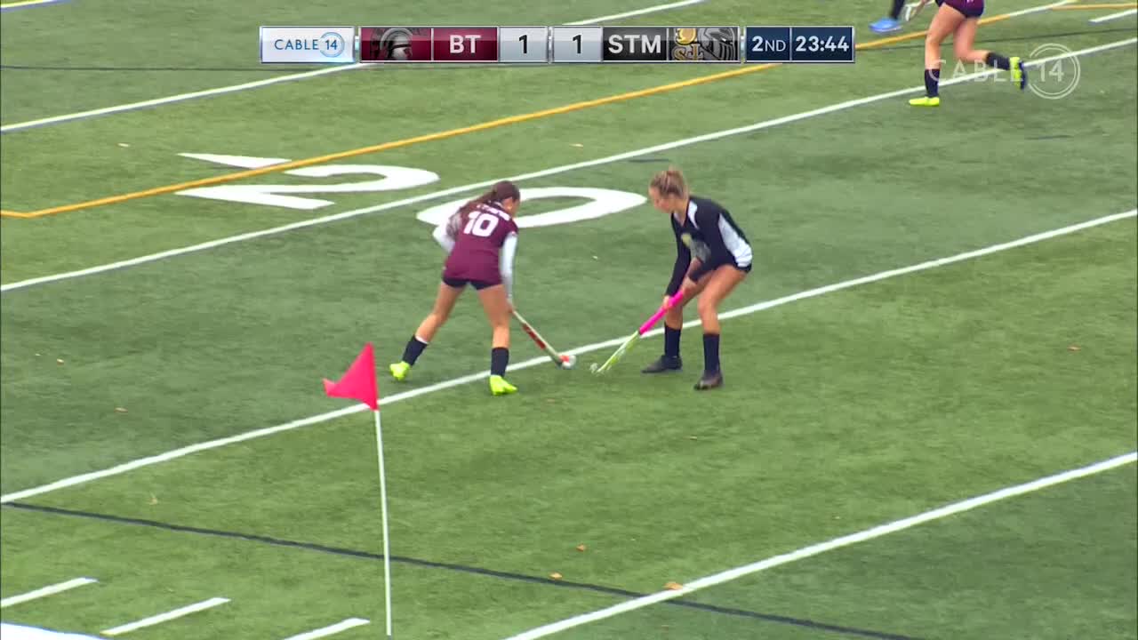 Two players, one in maroon and the other in black, face off on the field, sticks down, poised to strike. The Cable 14 Hamilton broadcast shows the score tied at one as the second half ticks away.
Two players, one in maroon and the other in black, face off on the field, sticks down, poised to strike. The Cable 14 Hamilton broadcast shows the score tied at one as the second half ticks away.