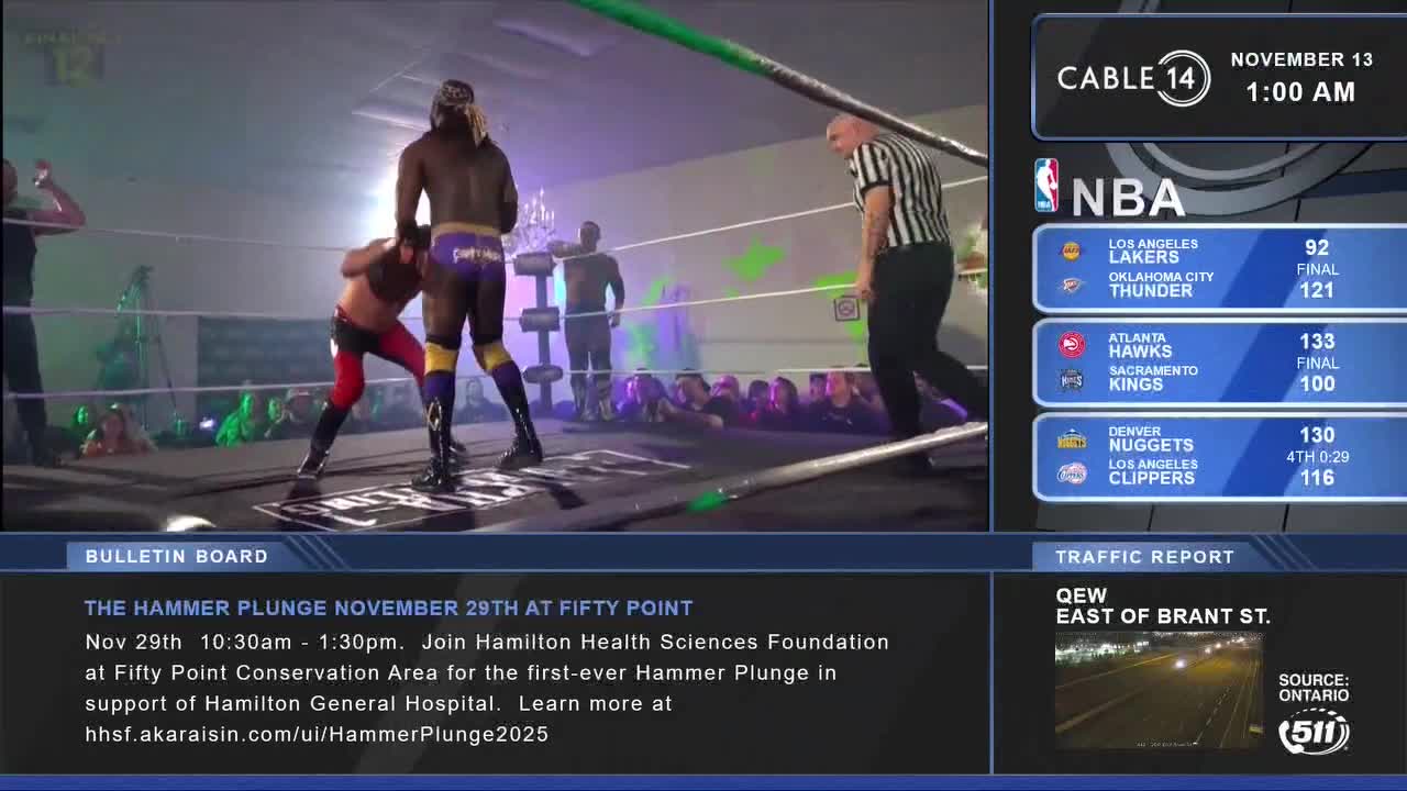 A wrestler in purple trunks has his hands on his opponent's head, the referee watching closely. Cable 14 Hamilton is broadcasting the scene, and the bulletin board promotes an upcoming event supporting the Hamilton General Hospital.
A wrestler in purple trunks has his hands on his opponent's head, the referee watching closely. Cable 14 Hamilton is broadcasting the scene, and the bulletin board promotes an upcoming event supporting the Hamilton General Hospital.