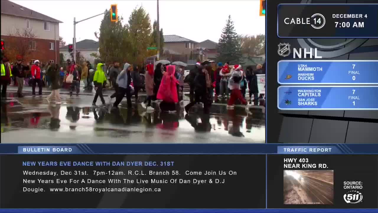 People are crossing the street, their reflections shimmering in the puddles on the road. The Cable 14 Hamilton broadcast shows the date is December 4th and the time is 7:00 AM.
