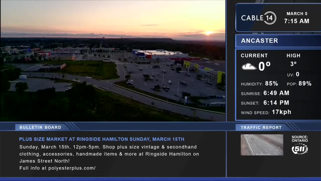 The sun is just starting to dip below the horizon, casting a warm glow over the Ancaster shopping plaza. Cars are scattered across the vast parking lot, their headlights beginning to pierce the twilight.
