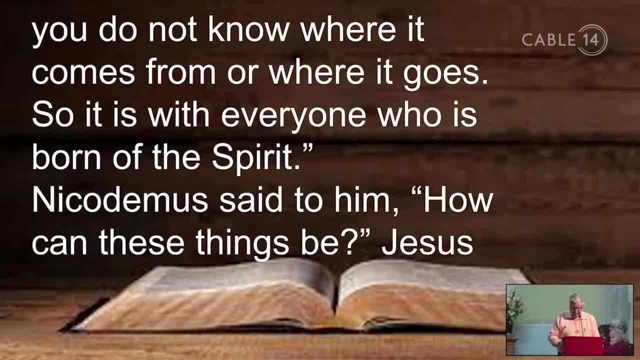 A man in a peach shirt stands behind a podium, speaking. The Cable 14 Hamilton logo appears in the upper right corner.