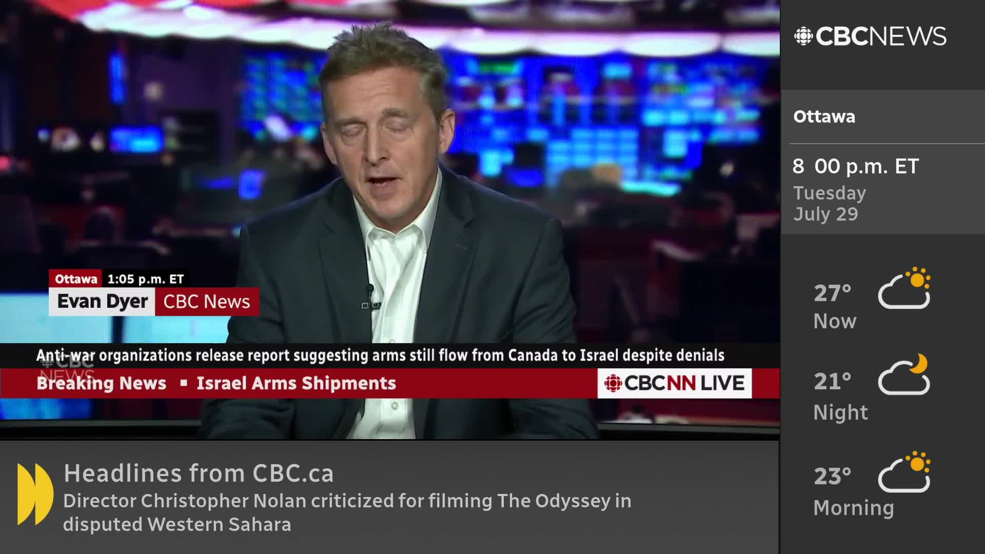 A man in a dark suit jacket and white shirt is speaking, his face lit by studio lights. The CBC News Network logo is visible, and headlines about arms shipments from Canada are displayed on the screen.
