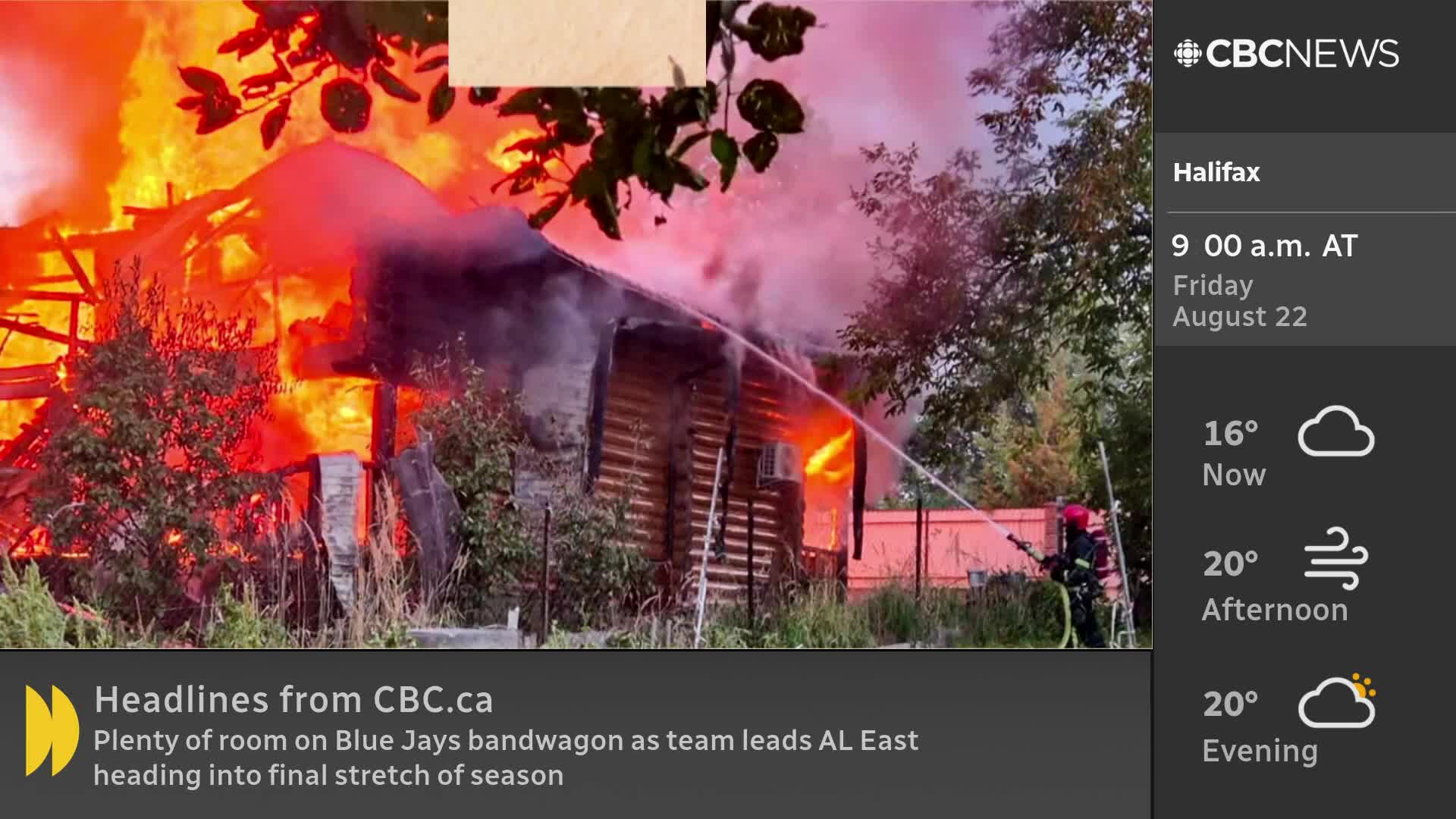 Flames consume a wooden building, with smoke billowing into the sky. A firefighter aims a hose at the blaze, trying to douse the intense heat.
