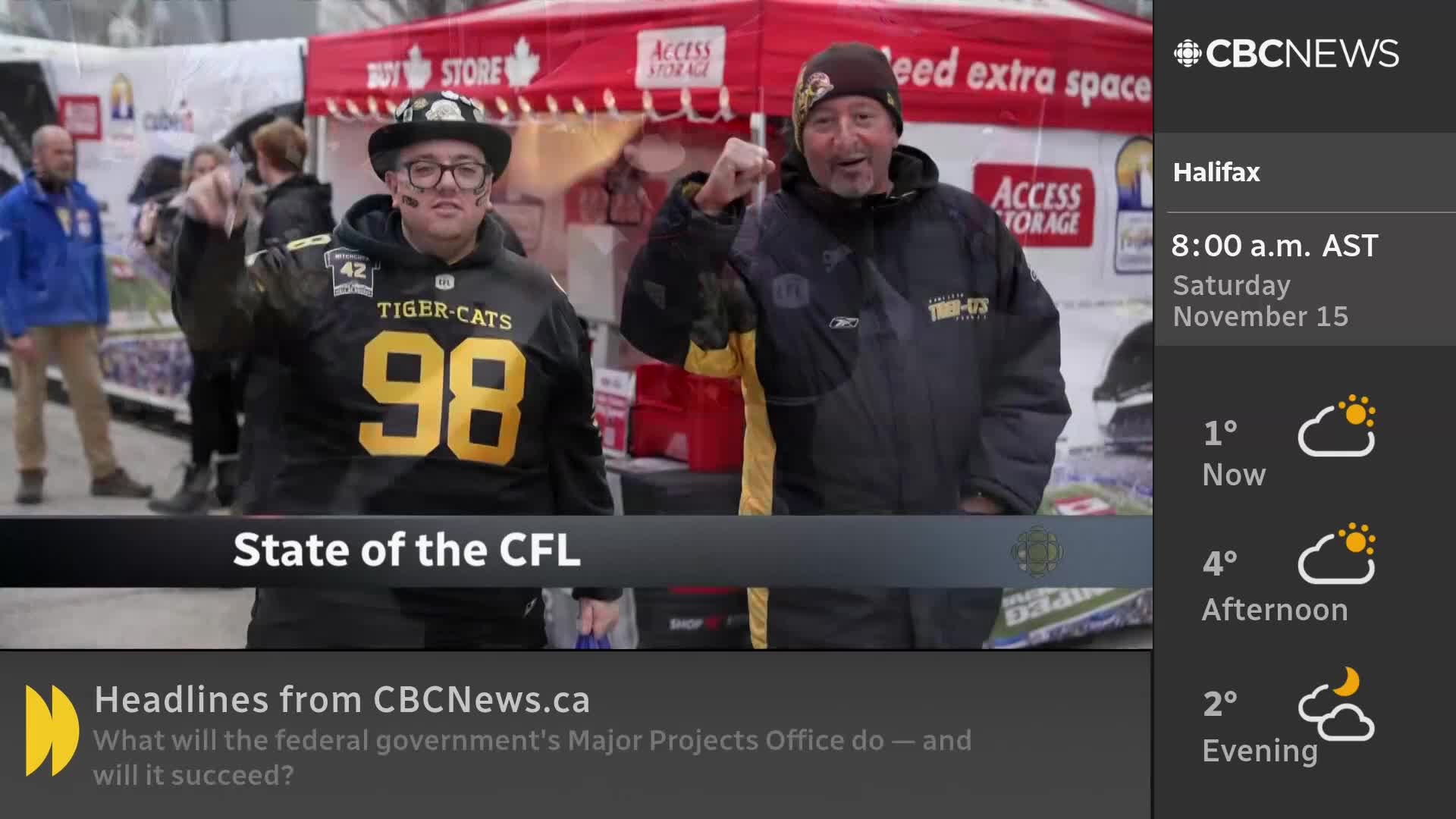 Two men, both wearing Tiger-Cats jerseys, are enthusiastically raising their fists. They're standing in front of a CBC News Network backdrop, likely discussing the CFL.
Two men, both wearing Tiger-Cats jerseys, are enthusiastically raising their fists. They're standing in front of a CBC News Network backdrop, likely discussing the CFL.