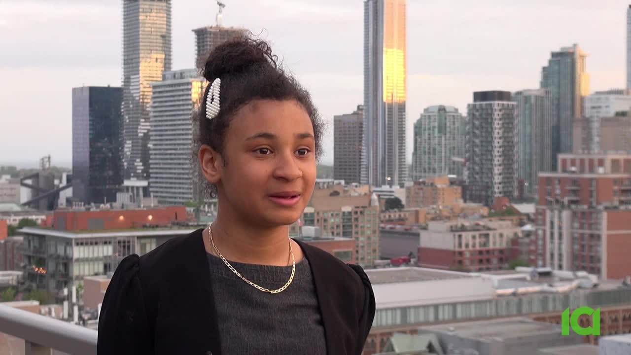 A young woman with her hair up is speaking, a cityscape of Toronto behind her. The CFHD-DT logo is in the corner.
