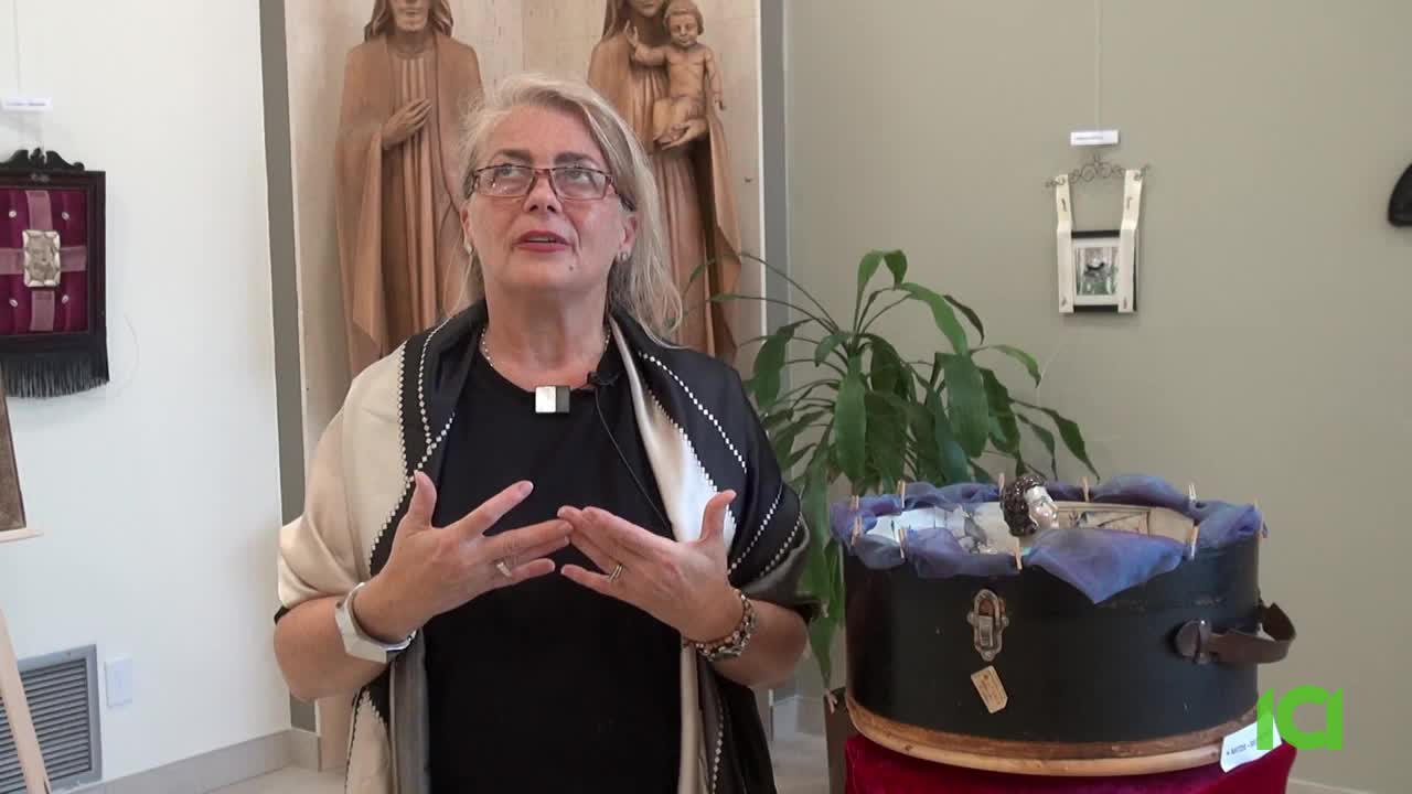 A woman in glasses gestures with her hands as she speaks, framed by a display of art and religious statues. The CFHD-DT logo is visible in the lower right corner.
