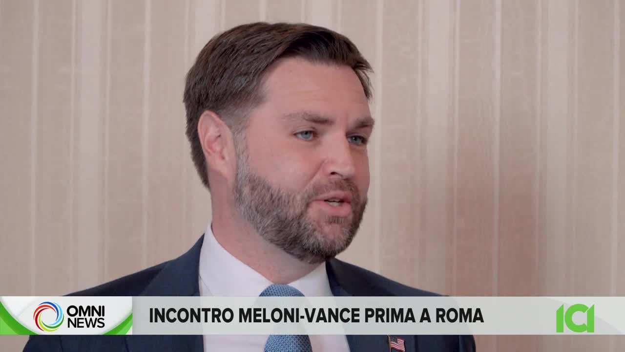 A man in a suit speaks, his blue tie patterned with small white dots. The Omni News logo appears in the lower left corner, with Italian text beneath it.