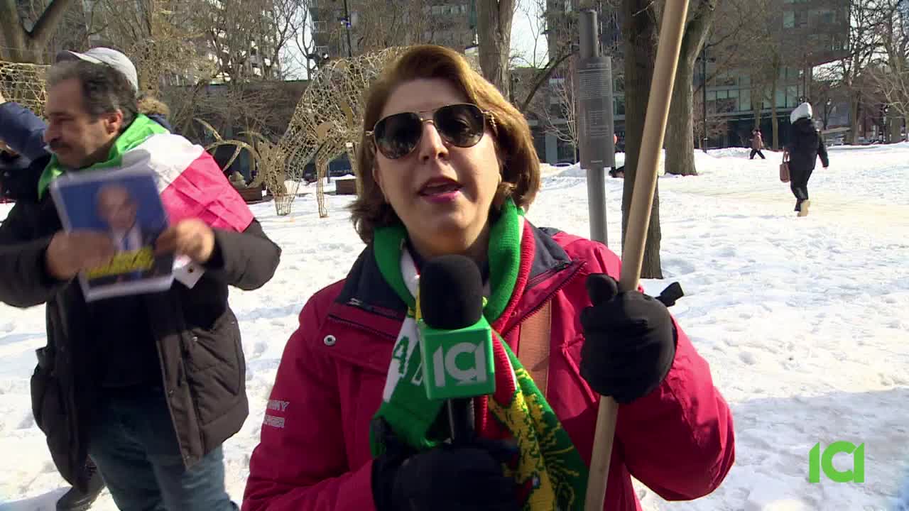 A reporter for ICI is speaking into a microphone, her scarf a vibrant green and red against the snow. To her left, a man holds up a portrait of a political figure, a Canadian flag draped over his shoulder.