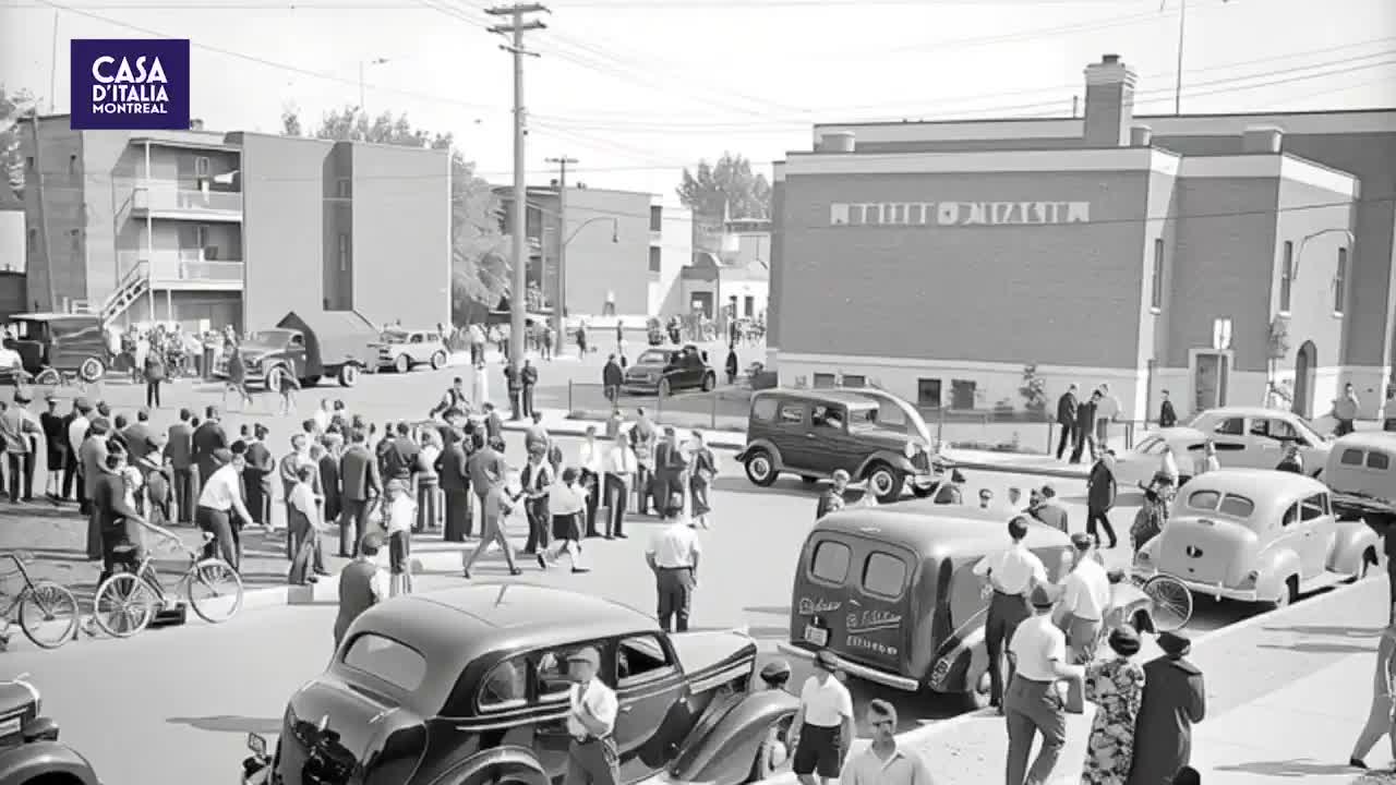 A crowd gathers on a Montreal street, with vintage cars parked and a few people on bicycles. The building behind them has "Casa d'Italia" emblazoned on its side. A crowd gathers on a Montreal street, with vintage cars parked and a few people on bicycles. The building behind them has "Casa d'Italia" emblazoned on its side.