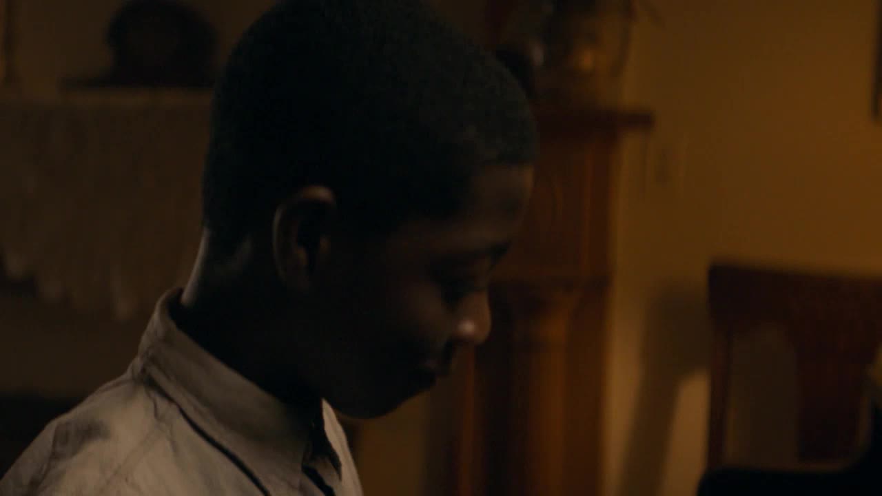 A young boy, dressed in a light-colored shirt, looks down intently. The warm, dim lighting suggests an indoor setting, perhaps a living room in Canada. A young boy, dressed in a light-colored shirt, looks down intently. The warm, dim lighting suggests an indoor setting, perhaps a living room in Canada.