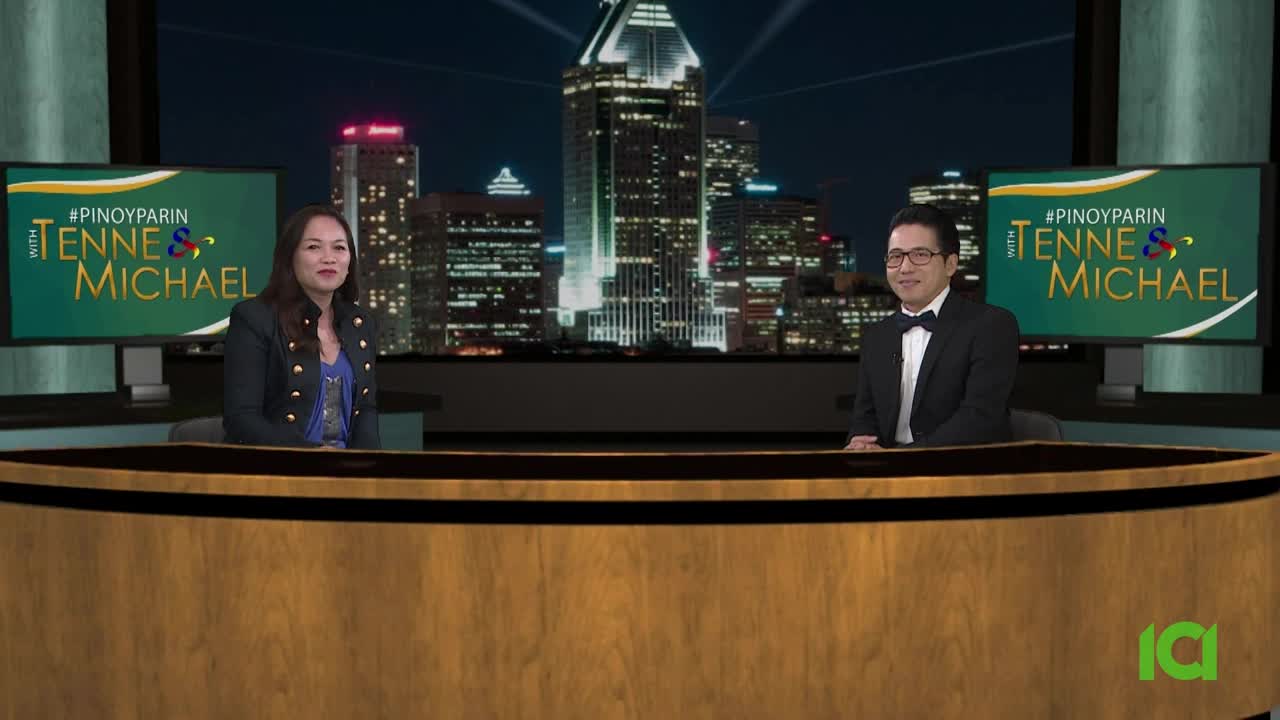 A woman in a dark jacket and a man in a tuxedo sit at a desk, bathed in the glow of studio lights. Behind them, a cityscape stretches across a screen, suggesting a broadcast from CFHD-DT in Canada.