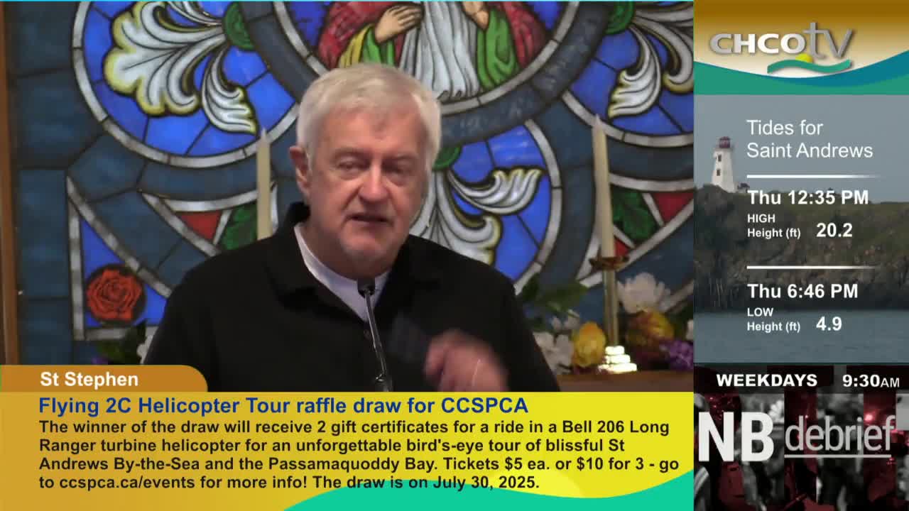 A man with white hair speaks into a microphone, likely on CHCO-TV from St. Stephen, Canada. The screen shows information about a helicopter tour raffle, alongside tide times for Saint Andrews.
