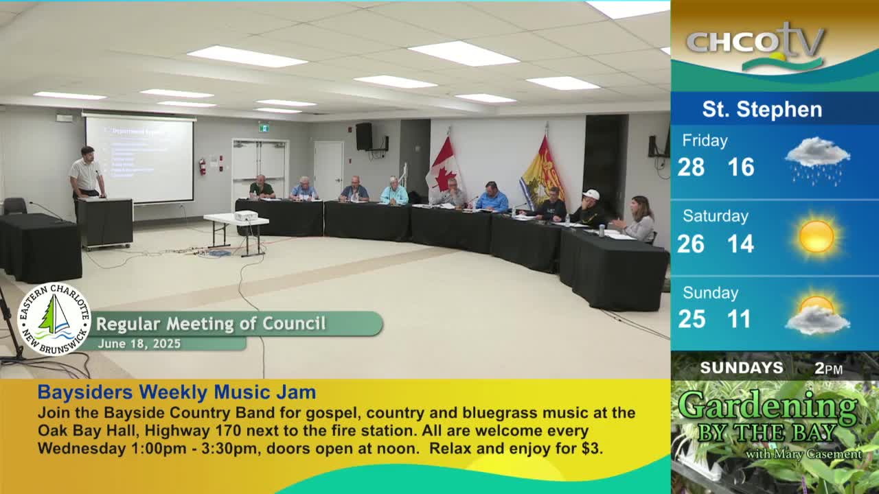 A man stands at a podium, speaking to a panel of people seated behind a long table. The CHCO-TV weather forecast for St. Stephen, Canada, is visible on the right side of the screen.
