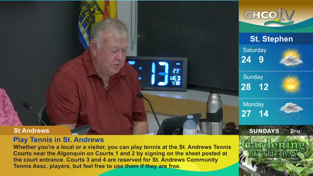 A man in a red shirt reads from a document, with a digital clock displaying the time behind him. The CHCO-TV weather forecast for St. Stephen is visible on the right side of the screen.
