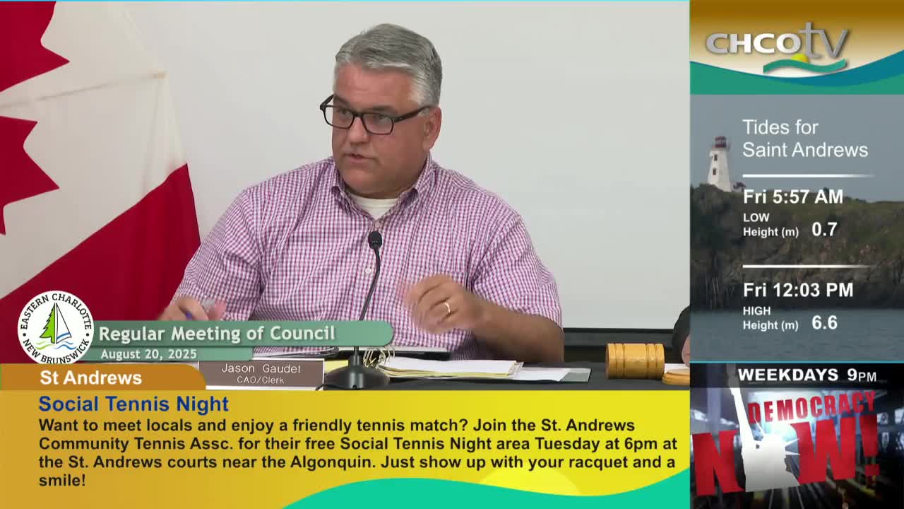 A man in glasses speaks into a microphone, gesturing with his hands during a council meeting. The CHCO-TV broadcast includes tide information for Saint Andrews and a promotion for a social tennis night.
