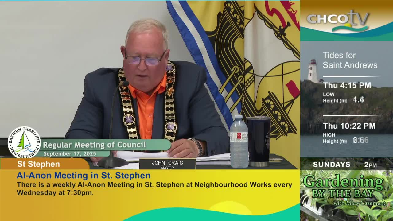 The mayor of St. Stephen, John Craig, is speaking at a council meeting, wearing a chain of office and an orange shirt. On CHCO-TV, the screen also shows tide information for Saint Andrews.
