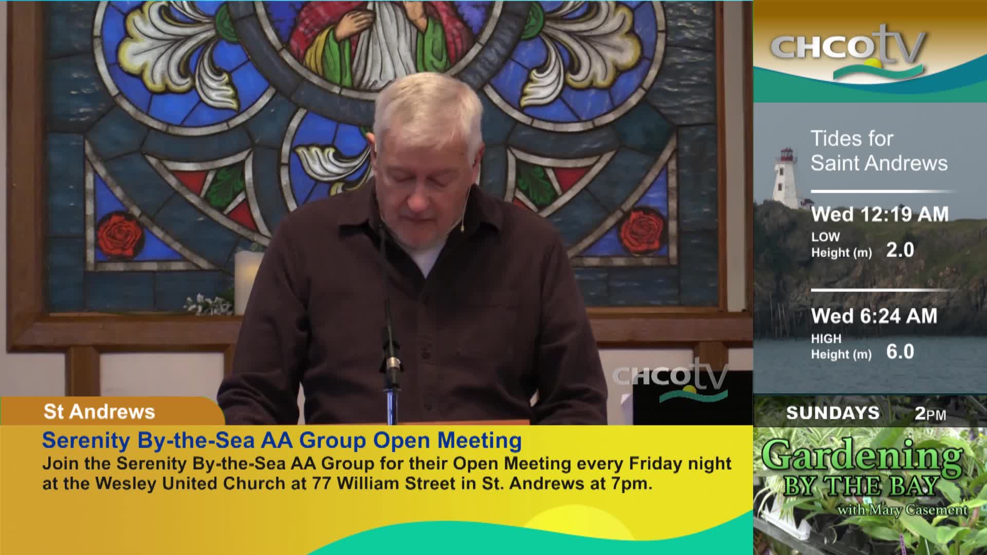 A man stands at a podium, reading from a paper. On the right, CHCO-TV displays the tides for Saint Andrews and a gardening program.