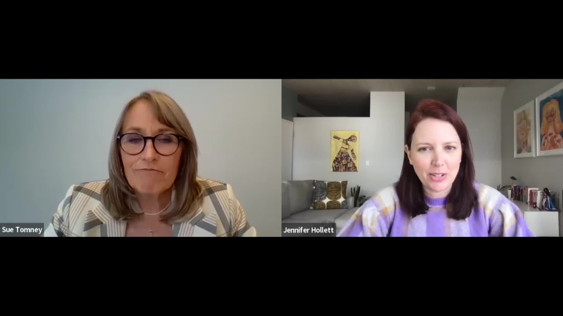Sue Tomney, wearing glasses and a striped blazer, looks thoughtfully towards the camera. To her right, Jennifer Hollett, in a purple sweater, speaks animatedly.