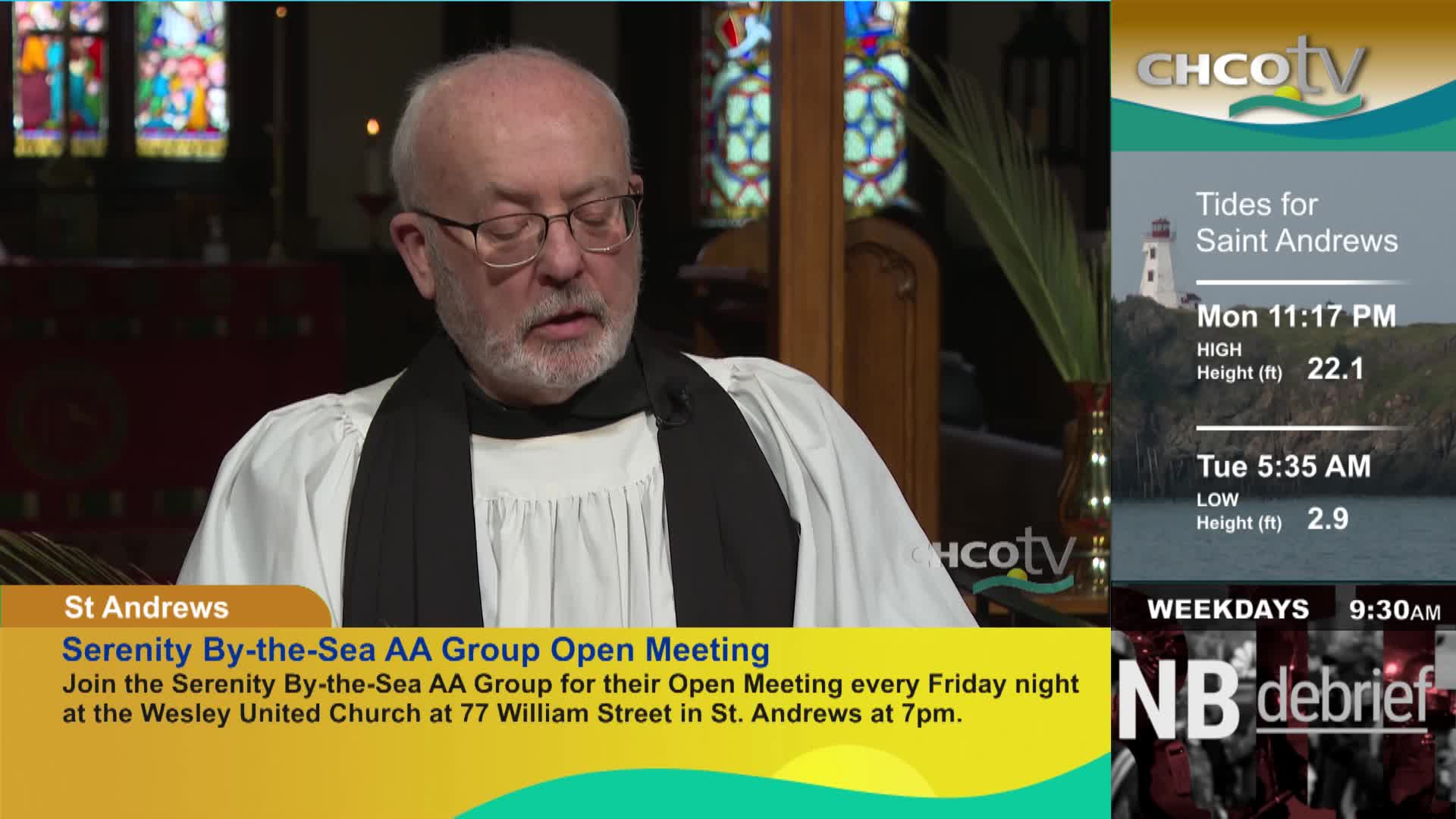 A man in clerical attire speaks, his glasses reflecting the light. To his right, a CHCOtv graphic displays tide information for Saint Andrews, New Brunswick.