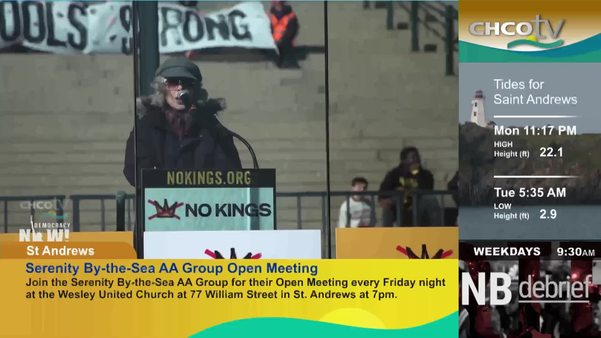 A woman with a grey ponytail and a cap speaks into a microphone at a podium. Behind her, a banner reads "SCHOOLS STRONG," and the podium itself displays "NOKINGS.ORG" and a "NO KINGS" logo.