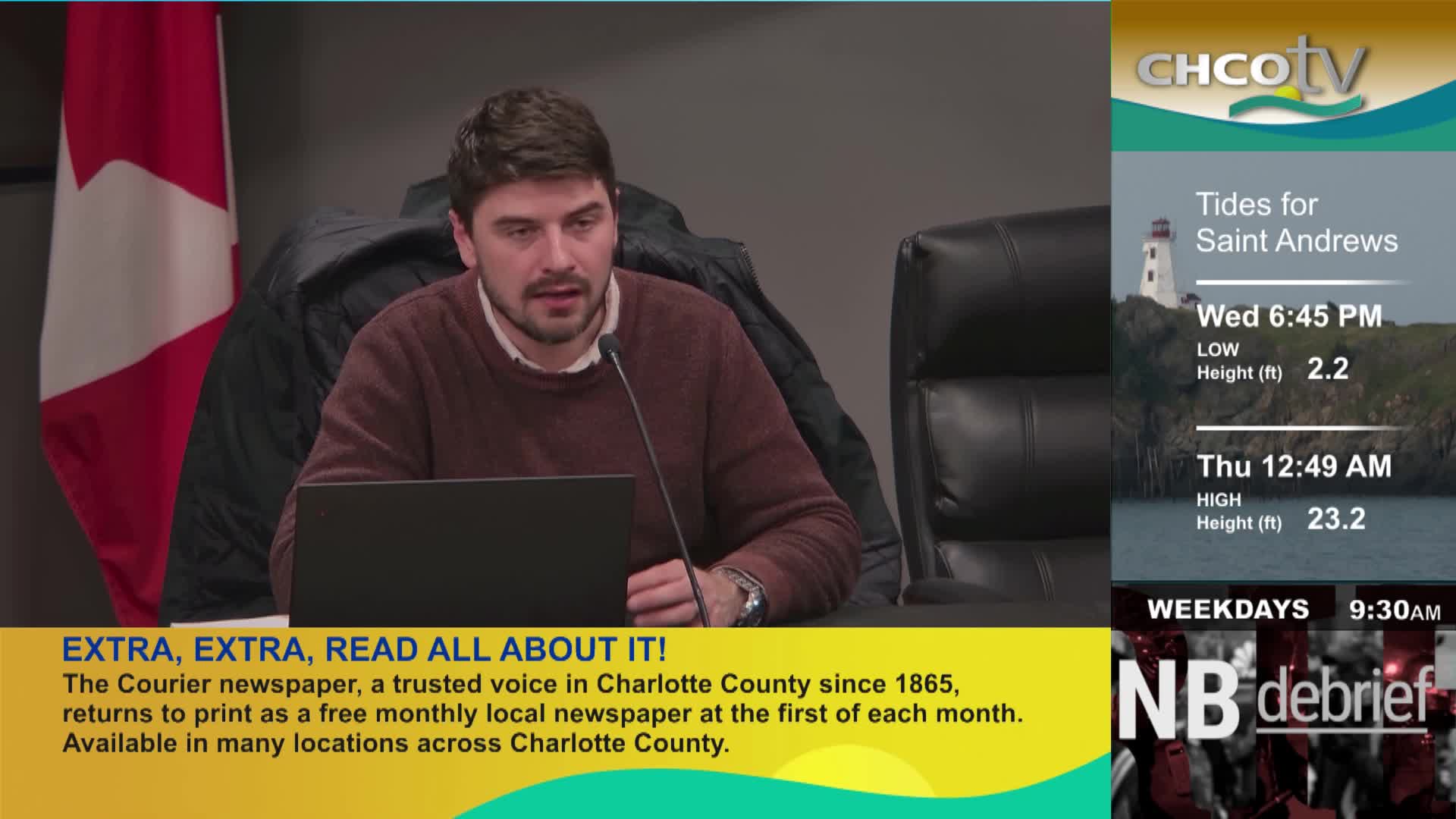A man speaks into a microphone, a Canadian flag behind him. On the right, CHCO-TV displays tide information for Saint Andrews. A man speaks into a microphone, a Canadian flag behind him. On the right, CHCO-TV displays tide information for Saint Andrews.