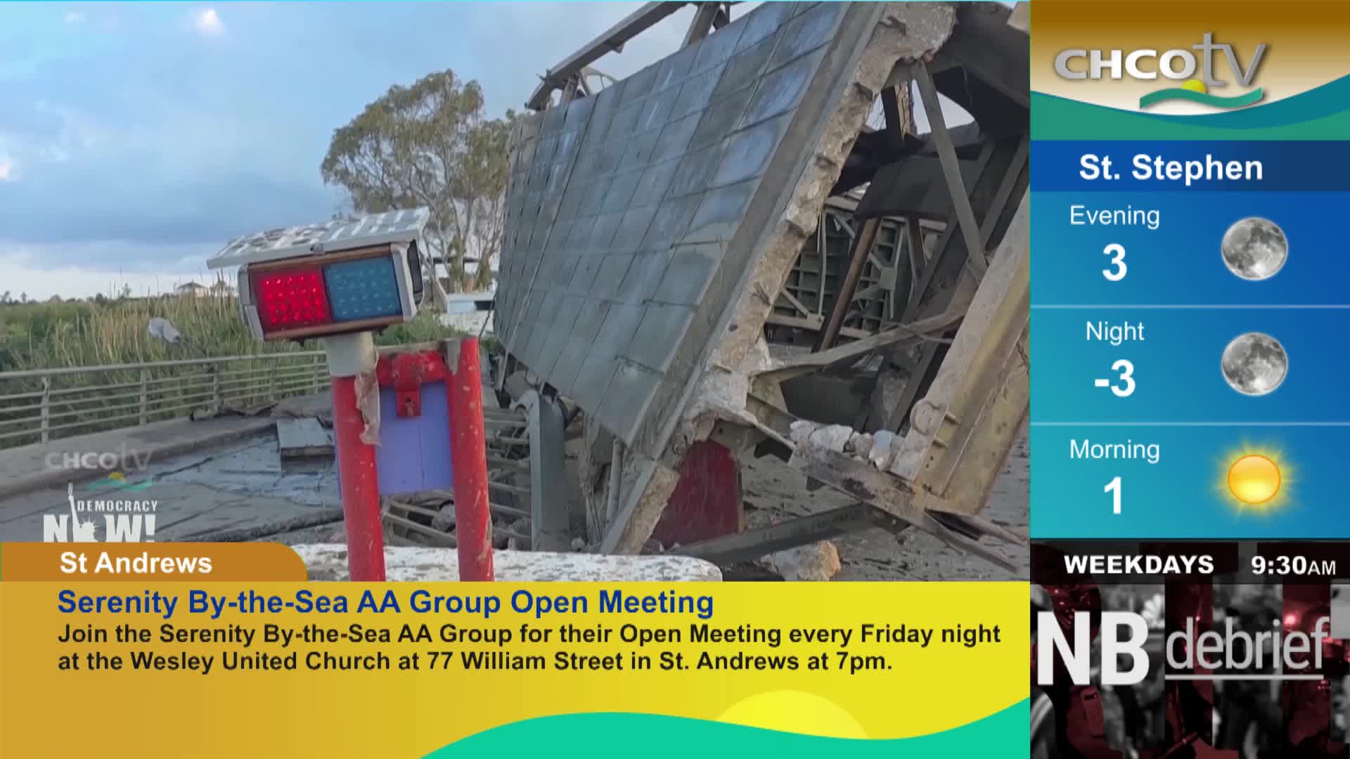 A traffic signal stands before a collapsed building. Debris litters the ground where the structure once stood.