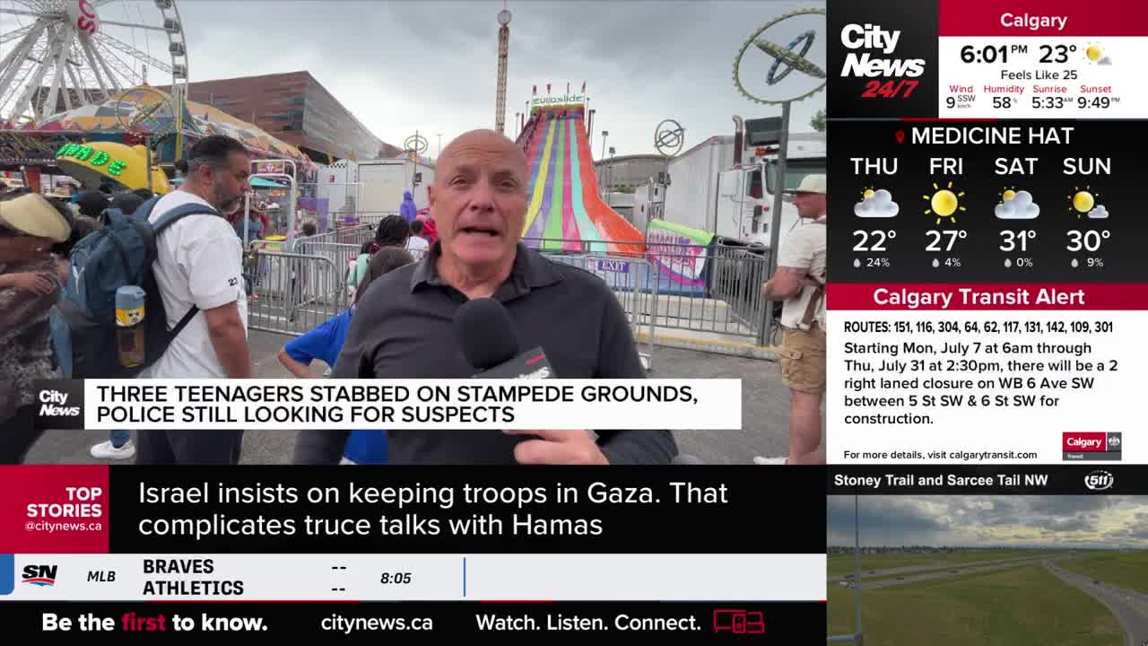 A CityNews Calgary reporter speaks directly to the camera, the Stampede grounds visible behind him. A colorful water slide and a Ferris wheel are in the background, as people mill about.
