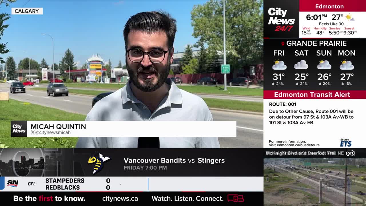 A reporter from CityNews Calgary stands on a sunny street, speaking into a microphone. Cars drive by on the road behind him, while a gas station sits in the distance.
