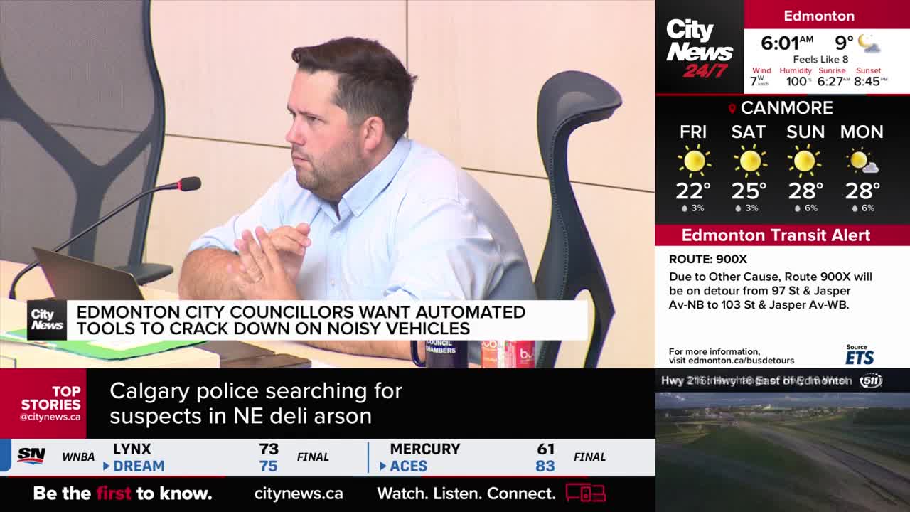A man in a light blue shirt sits at a table, facing a microphone. The CityNews Calgary logo and a headline about Edmonton city councillors are visible on the screen behind him.

