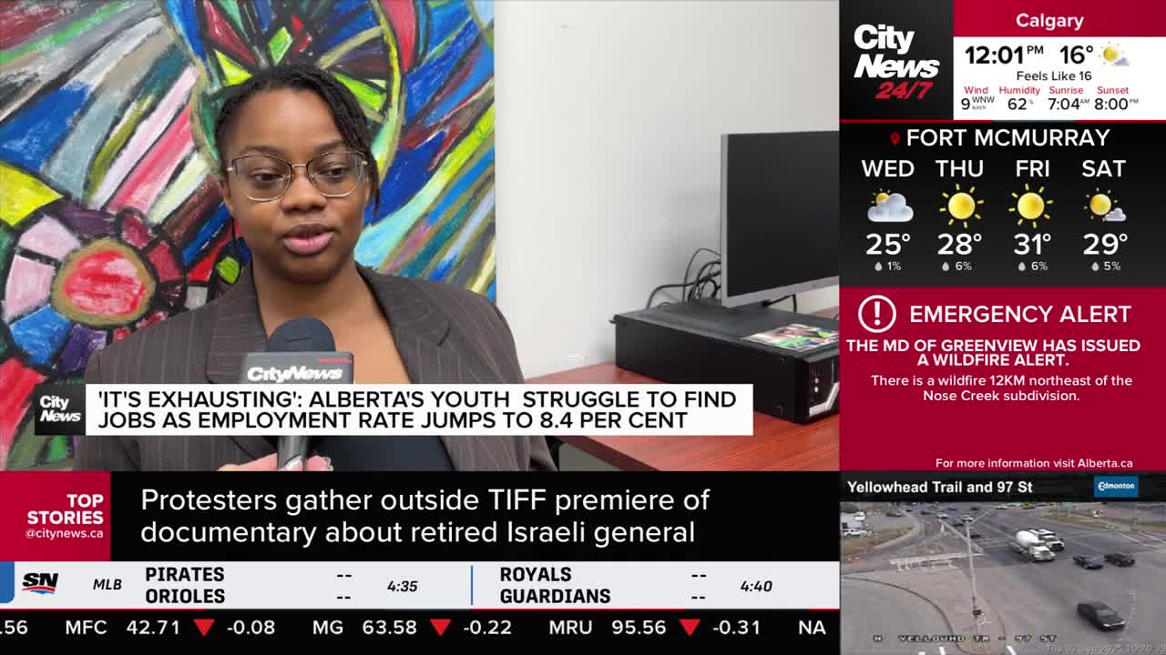 A CityNews Calgary reporter, wearing glasses and a blazer, speaks into a microphone. The screen beside her displays the current Calgary weather and an emergency wildfire alert.
