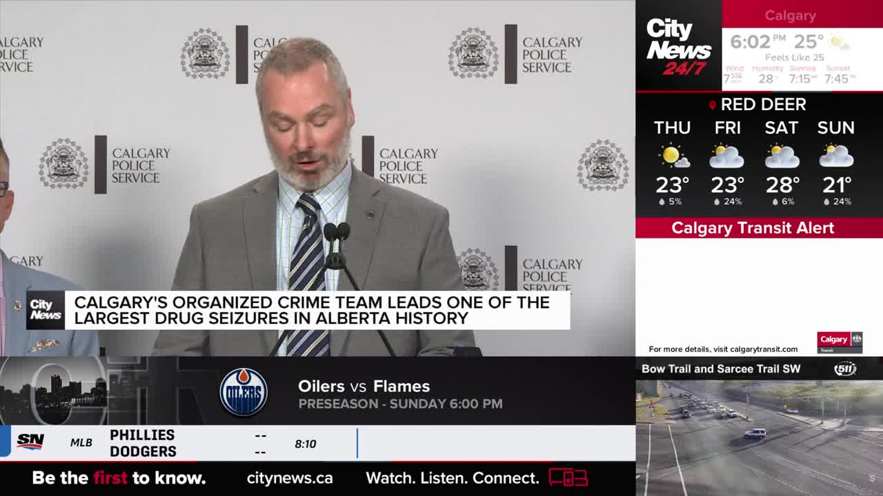 A man in a suit speaks into a microphone, addressing the press, as the CityNews Calgary logo appears on the screen. The headline reads "Calgary's Organized Crime Team Leads One of the Largest Drug Seizures in Alberta History."
