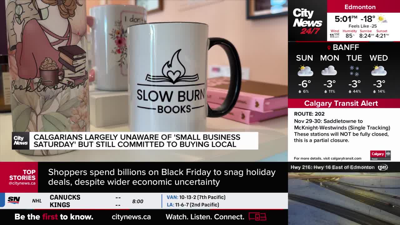 A "Slow Burn Books" mug, with a black handle, sits front and center, displayed with other mugs and books. CityNews Calgary's screen shows the weather and transit alerts, as well as a headline about local shopping.
