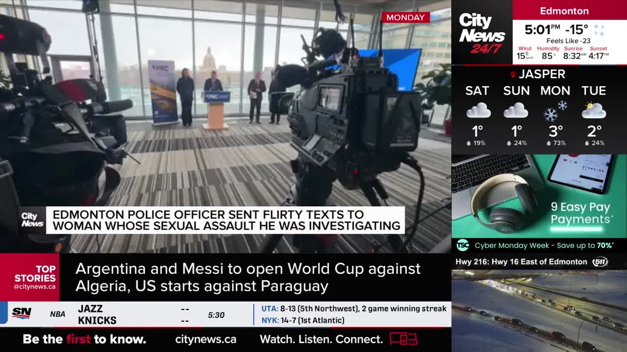 A large camera is positioned in the foreground, facing a podium where three people stand. The CityNews Calgary logo is visible on the screen, reporting on an Edmonton police officer.
A large camera is positioned in the foreground, facing a podium where three people stand. The CityNews Calgary logo is visible on the screen, reporting on an Edmonton police officer.