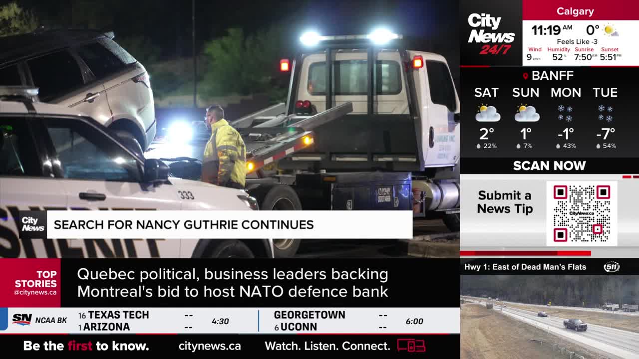 A tow truck is lifting a white SUV onto its flatbed, with a sheriff's vehicle parked nearby. A man in a high-visibility jacket stands by the scene, illuminated by flashing lights.
