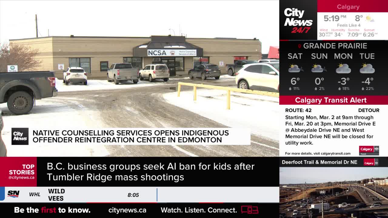 A white SUV is parked in front of the NCSA building. Several other vehicles are also present in the snowy lot.
