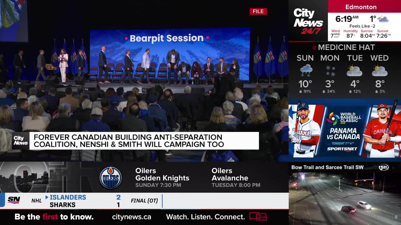 A woman in a white suit stands at a podium, addressing a crowd seated in rows. On a large screen behind her, the words "Bearpit Session" are displayed.