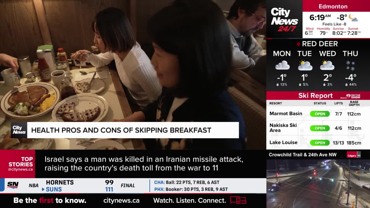 People are gathered around a table, eating breakfast. A news ticker scrolls by, showing a story about an attack in Iran.