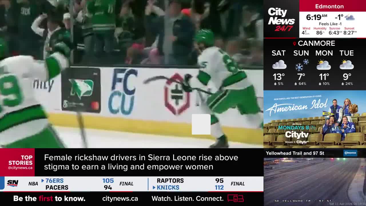 A hockey player in a green and white jersey skates hard, stick on the ice. Another player in the same uniform is ahead, also on skates.