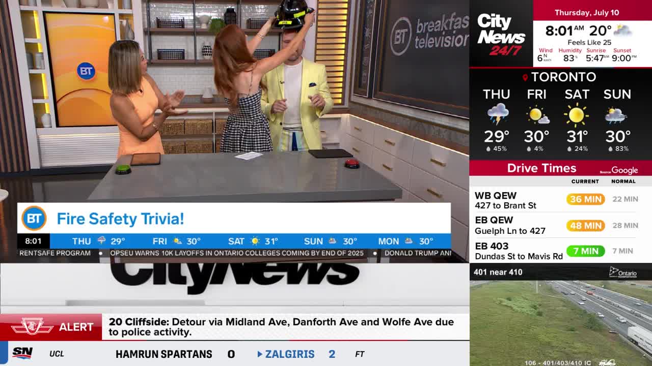 On the set of CityNews Toronto's "Breakfast Television," a woman is placing a firefighter's helmet on a man's head. Across the studio, another woman watches, clapping her hands.
