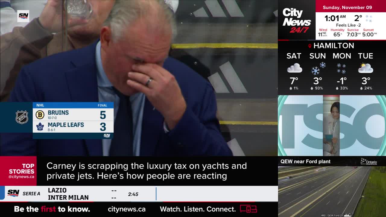 The man in the blue suit is wiping his face, his expression hidden. A CityNews Toronto graphic shows the Bruins beating the Maple Leafs, and the score is displayed.
