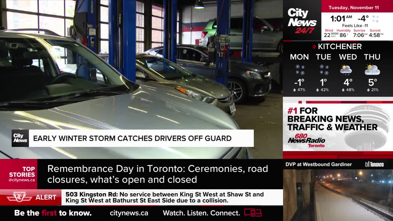 Inside a garage, several cars are parked, some on lifts. The CityNews Toronto screen reports on an early winter storm, which has caught drivers off guard.

