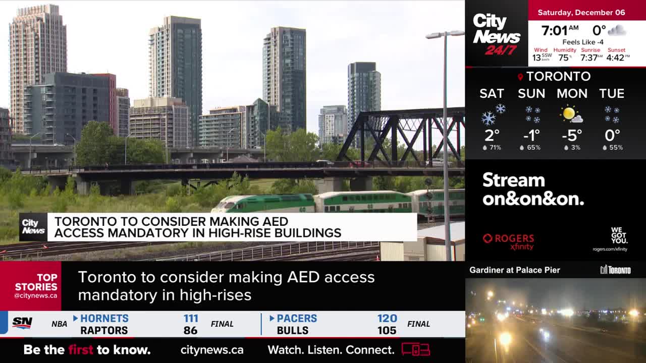 A green and white GO train is moving across the tracks in front of the Toronto skyline. CityNews is reporting on the city's consideration of making AED access mandatory in high-rises.
