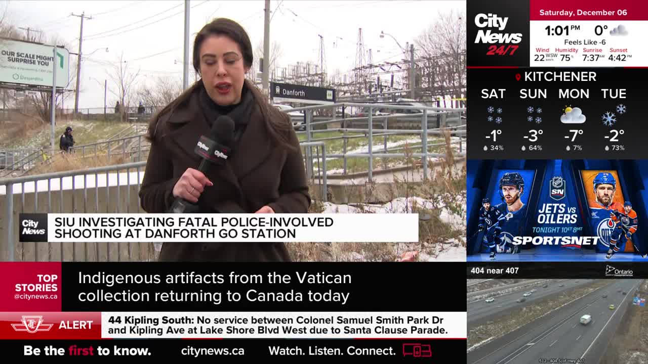 A CityNews Toronto reporter stands at the Danforth GO Station, speaking into a microphone. Behind her, a person in dark clothing is visible near the tracks.
