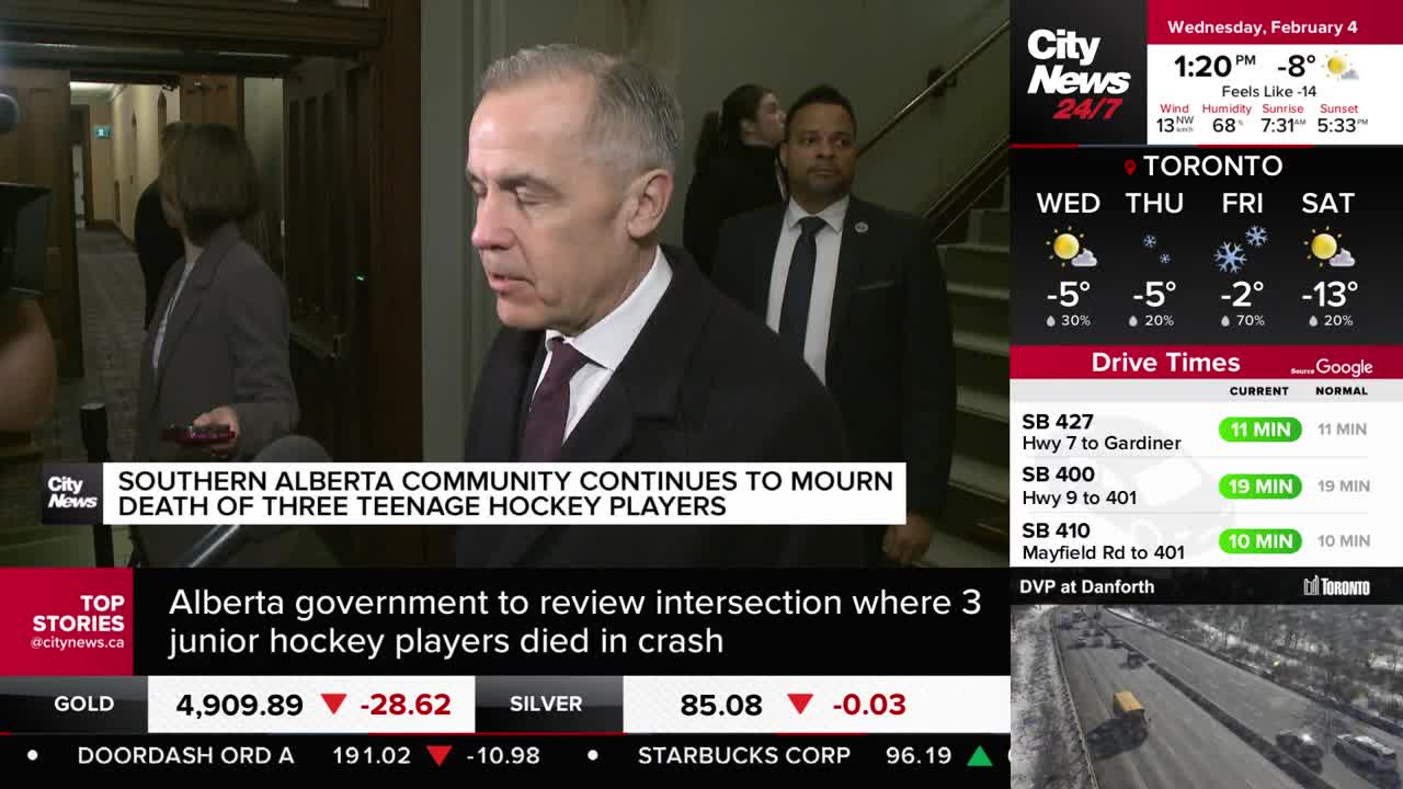 A man in a dark suit and tie walks past a news camera, his expression somber. Behind him, another man in a suit follows closely.