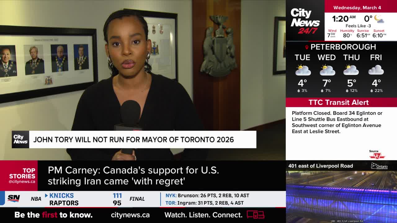 A reporter stands holding a microphone, delivering news about John Tory not running for mayor in Toronto 2026. On the screen behind her, a weather forecast for Peterborough shows cloudy skies and mild temperatures.