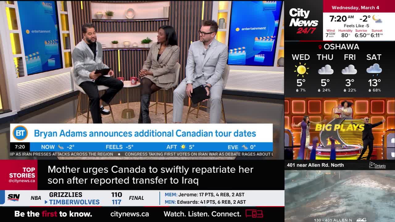 A man in a grey cardigan and a woman in a patterned blazer are seated on stools, engaged in conversation. On the screen behind them, a graphic displays "Entertainment."