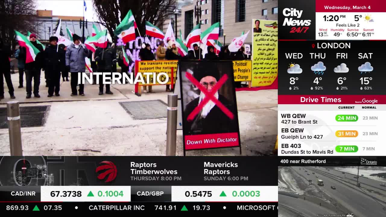 A group of people stand holding Iranian flags, some with banners that read "We Iranians residing in Canada support the national..." and "Political Change." A sign in the foreground displays a picture of a man with a red X over his face and the words "Down With Dictator."