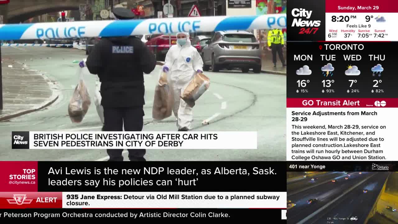 Police tape stretches across the street, blocking off the scene. Two officers, one in uniform and another in a white protective suit, carry large bags of evidence.