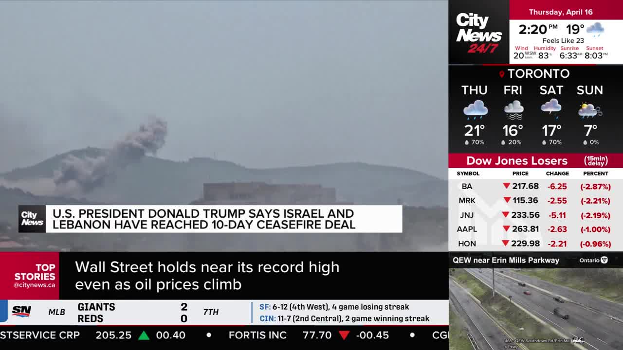 A plume of smoke rises from a distant hillside. Down below, a news ticker scrolls with headlines about international affairs and market fluctuations.